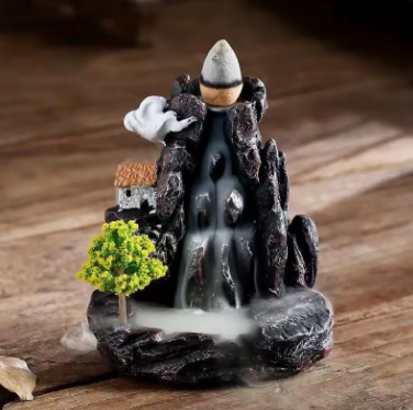 Decorative incense burner shaped like a mountain with trees on a wooden surface