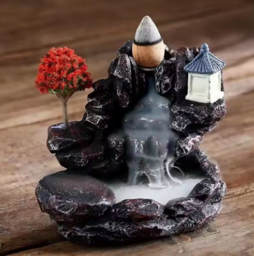 Decorative incense burner with a mountain and tree design on a wooden surface