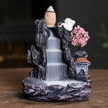 Decorative water fountain with rocks and a tree on a wooden surface