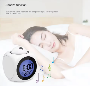 Digital alarm clock with snooze function displayed next to a person sleeping