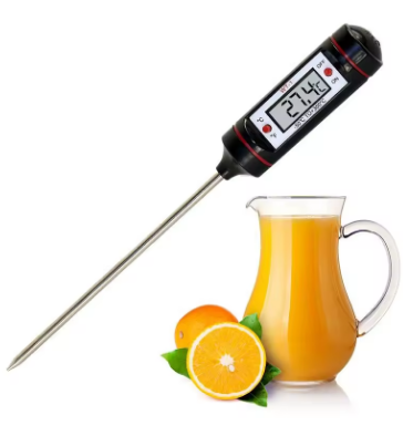 Digital thermometer inserted into a pitcher of orange juice with oranges on a white background