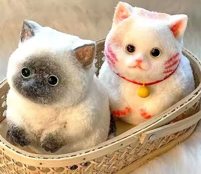 Two plush cat toys, one gray and one white with red accents, in a woven basket.